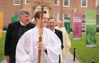 Brs. David Van Hollebeke, FSC, and James Wallace, FSC, follow the cross-bearer during a religious procession through The Quad at Manhattan College.